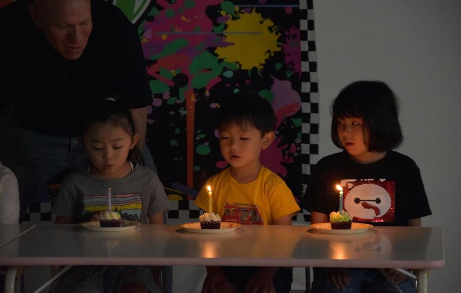 ヒルトップインターナショナルスクールで誕生日ケーキのろうそくを吹き消す子どもたち